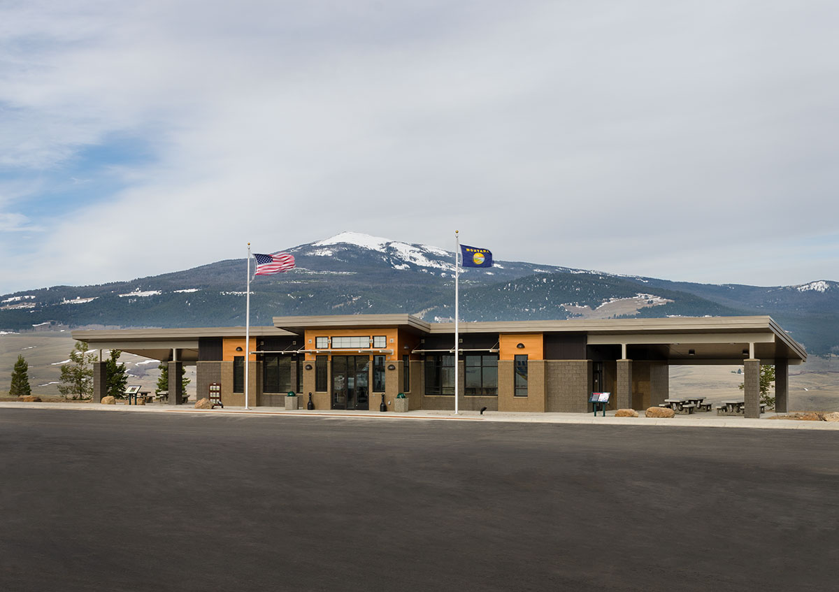 Montana rest area in Divide with the American flag and Montana flag in front of a snow covered mountain