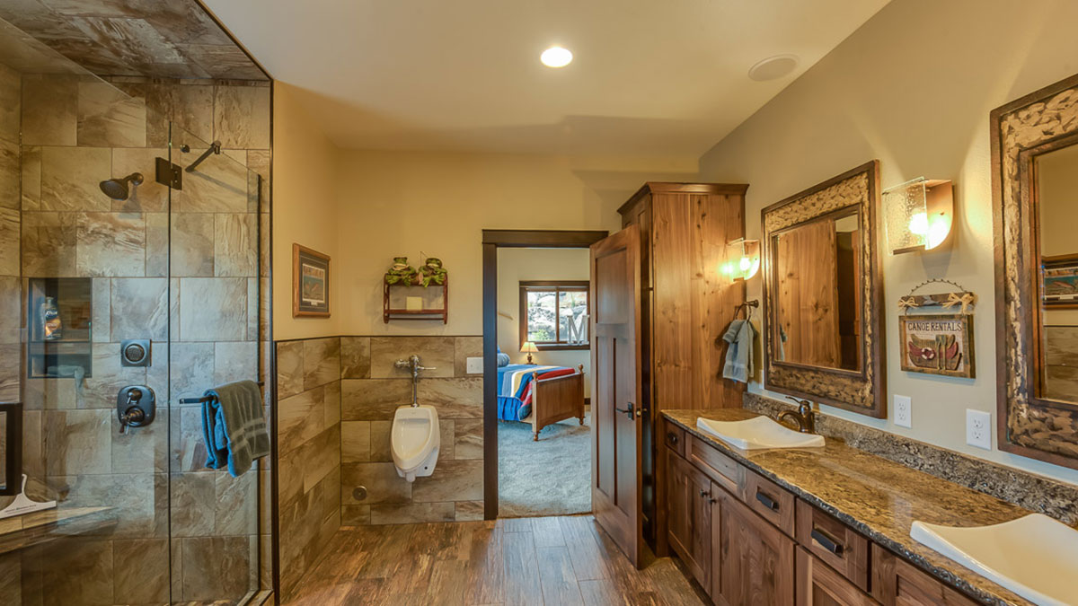 Bathroom with walk in shower to the left and a granite countertop with custom sinks on the right with a view of the bedroom